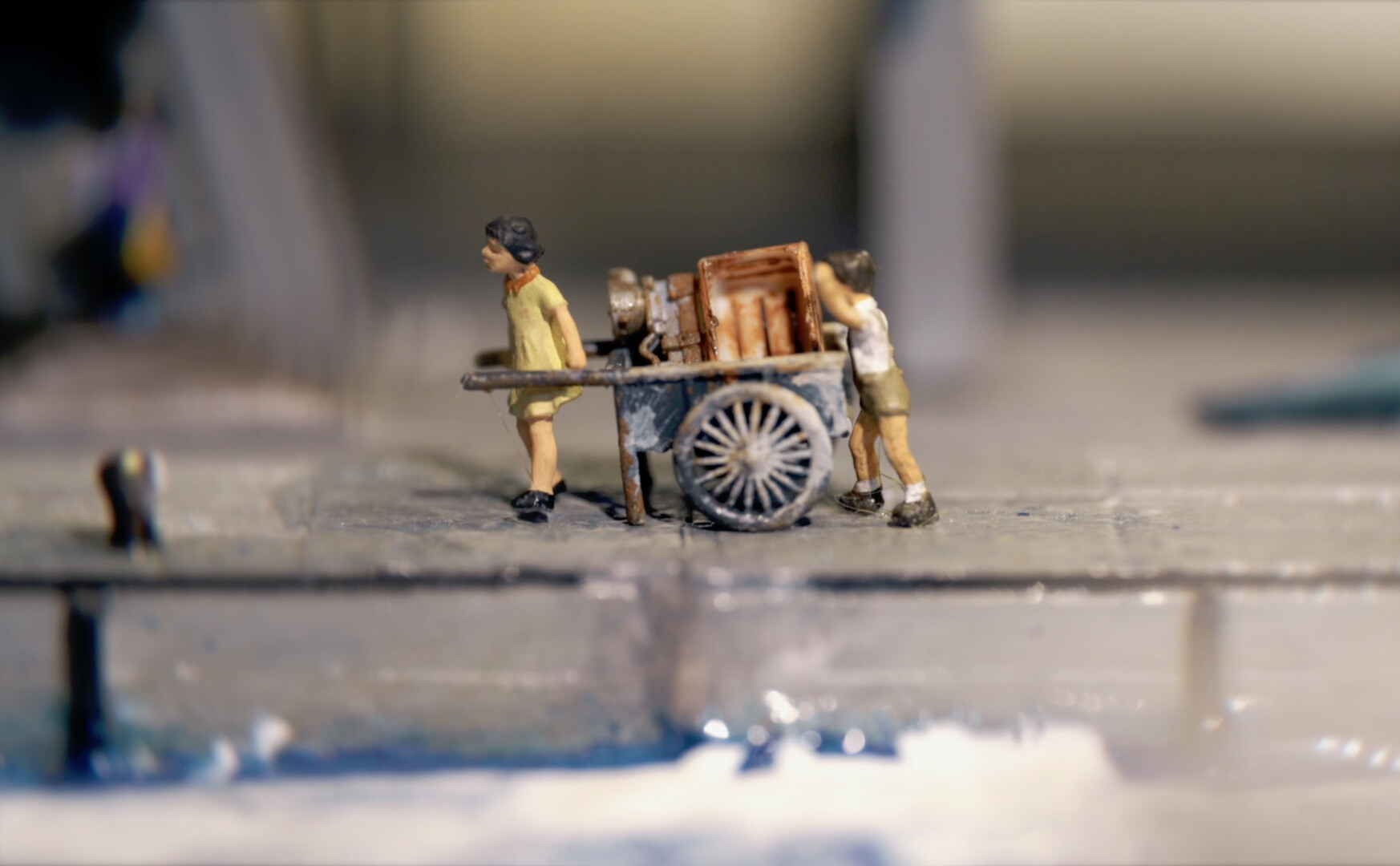 Still from The Siblings&rsquo; Cart &mdash; miniature figures pulling a wooden cart, blending live-action with miniature filmmaking