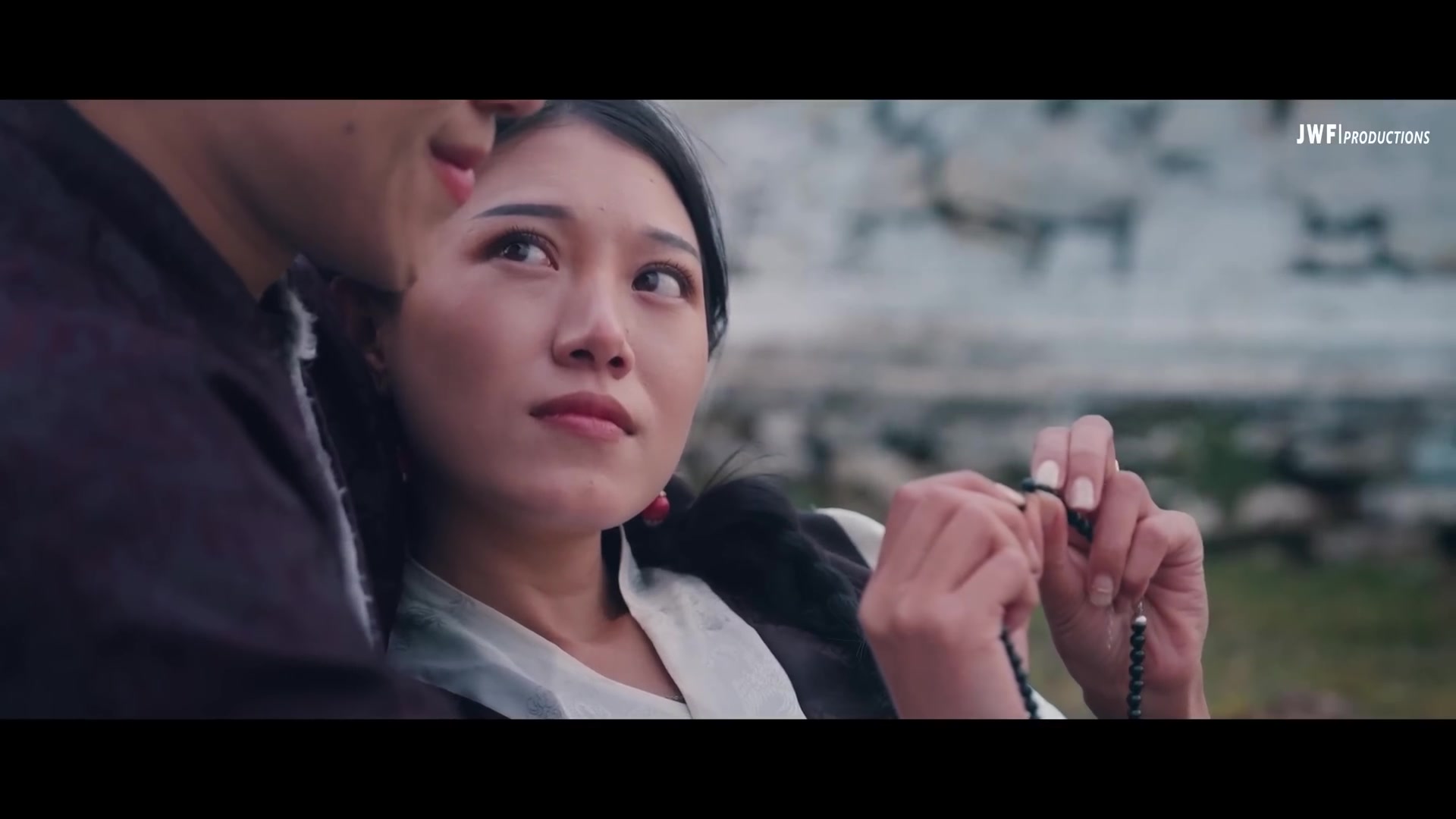 Production still from Tshangyang &mdash; A Love Beyond Dharma: the lovers in a Bhutanese highland, Tshangyang holding a string of prayer beads while his beloved gazes at him in tender longing